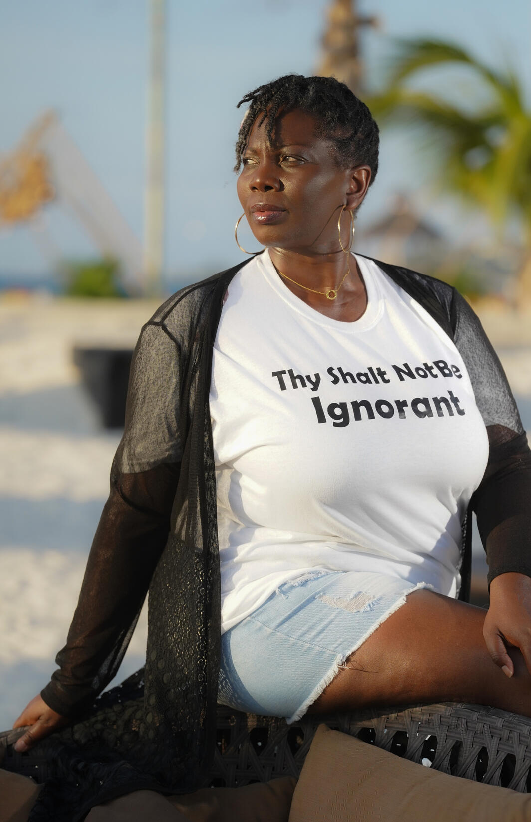 Regina wearing a white t-shirt with the words Thy Shall not be ignorant and a black knitted jacket on top